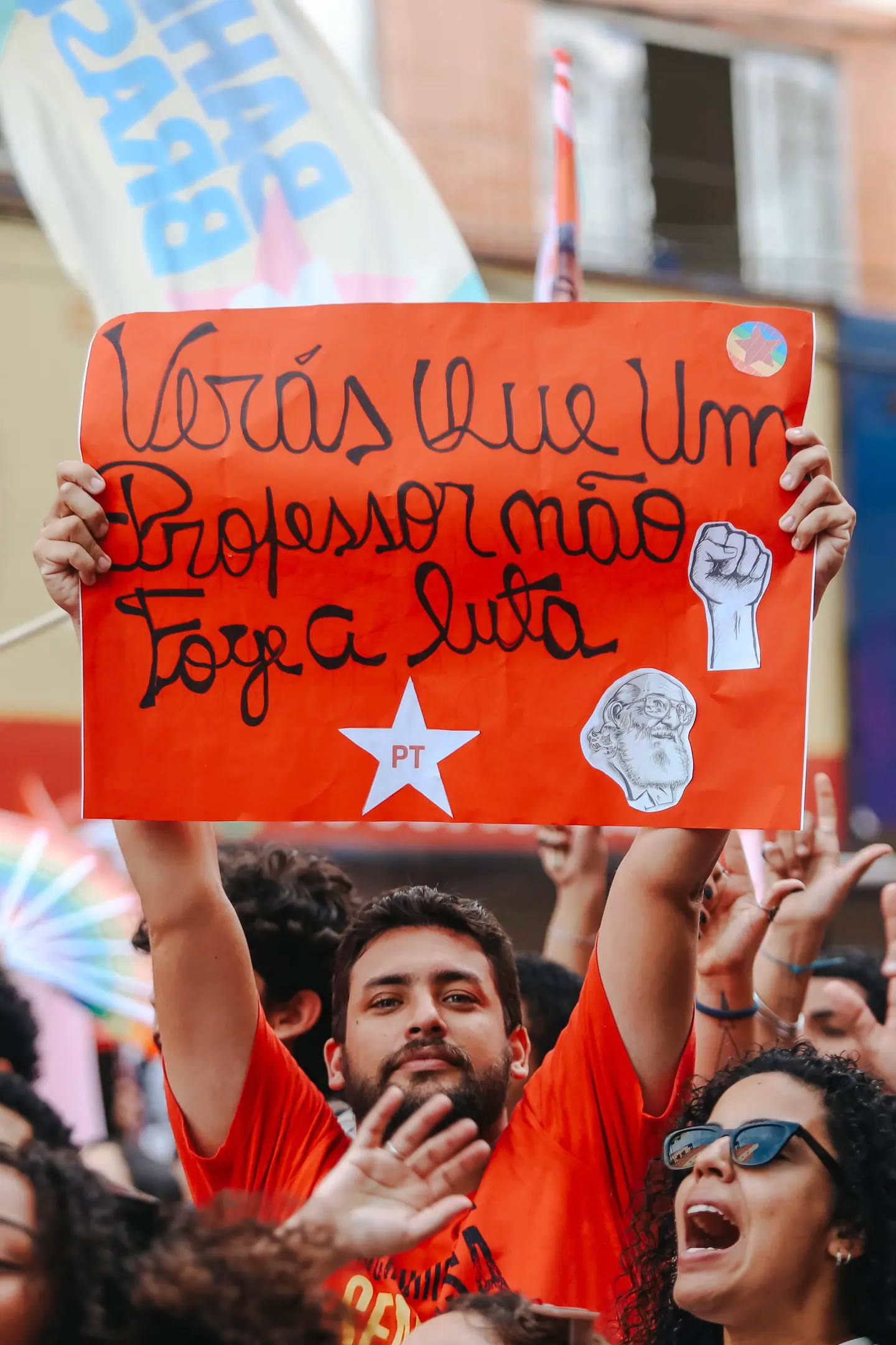 Manifestante ergue cartaz escrito à mão em meio à multidão