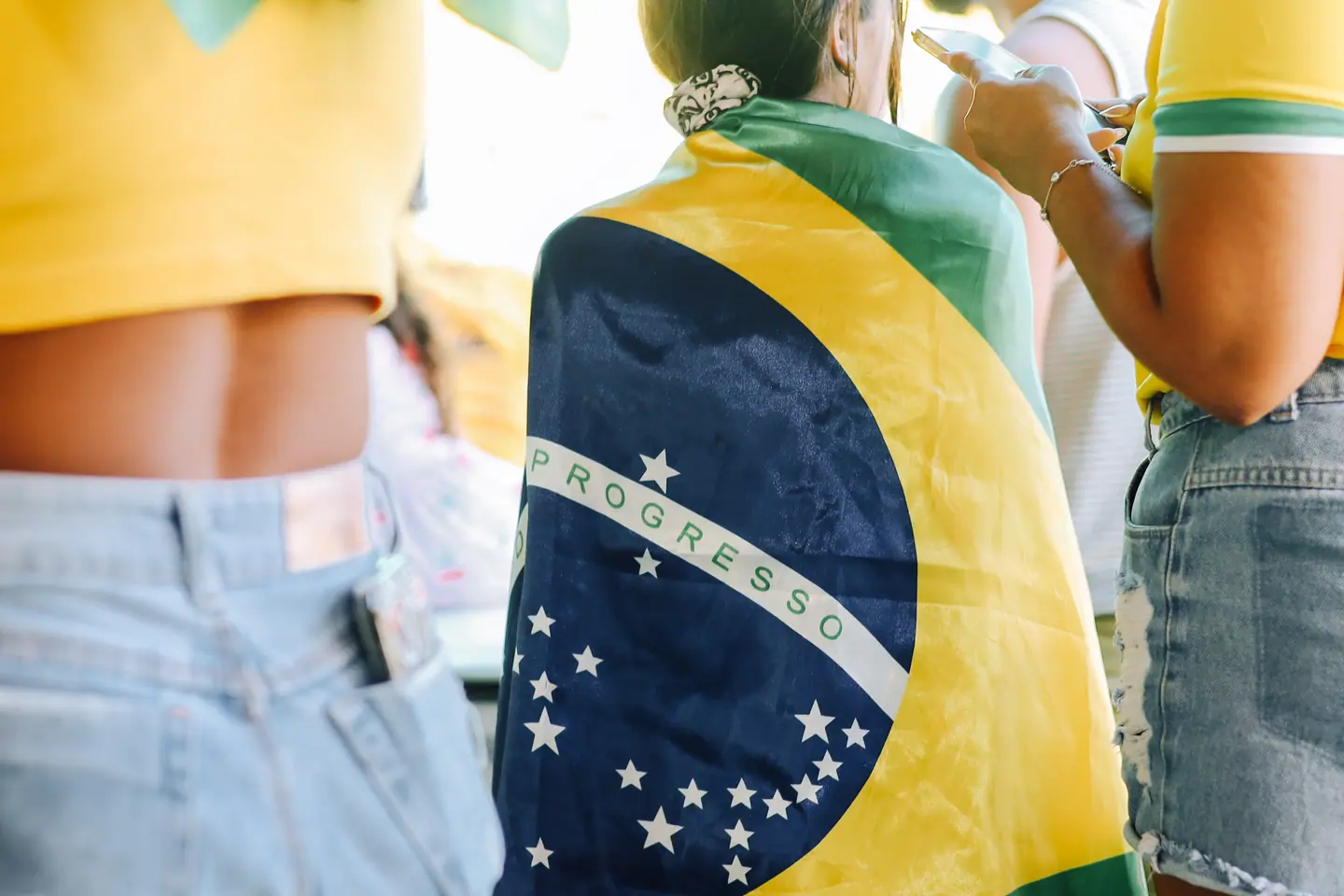 Jovens com a bandeira do Brasil nas costas em dia de jogo