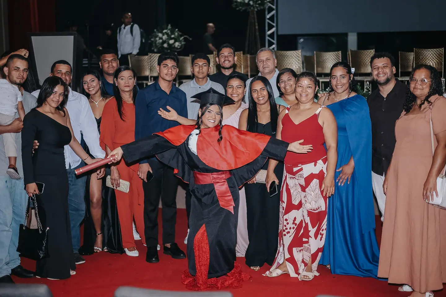 Formanda deitada nos braços da família sobre o tapete vermelho