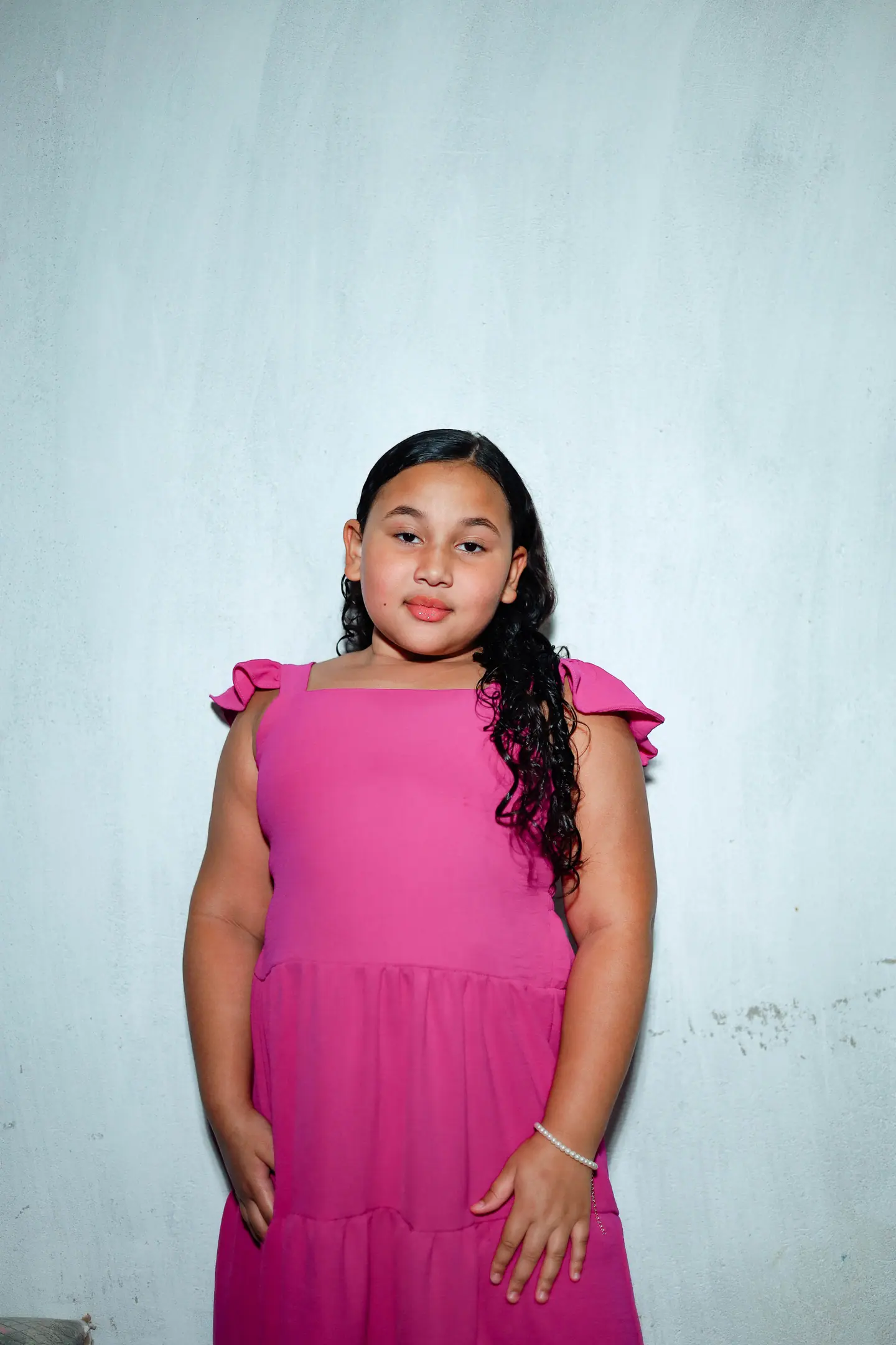 Retrato de menina de vestido rosa contra parede clara