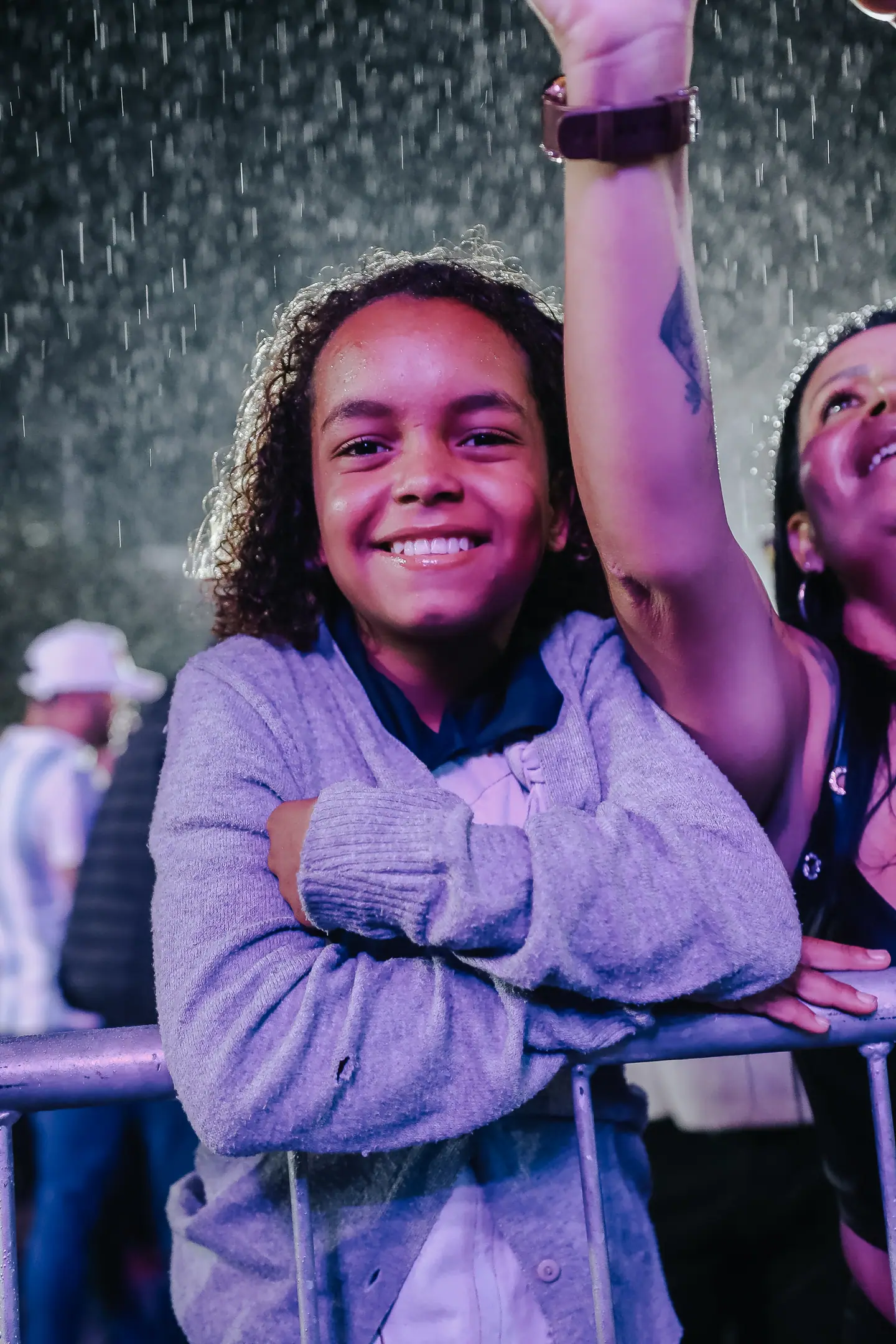 Menina sorri na grade do show enquanto cai chuva de espuma